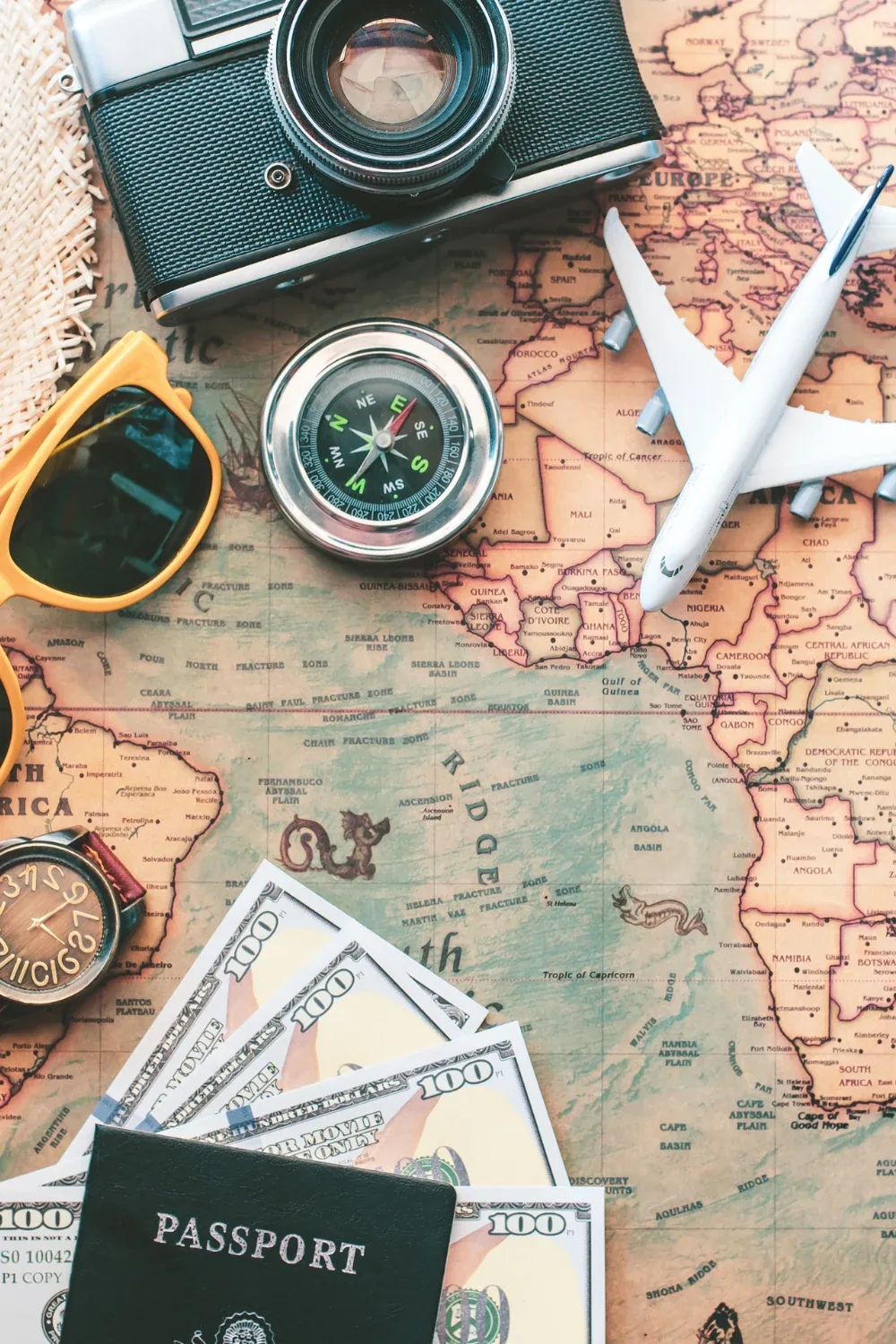 US tourist travel visa — passport, dollars, camera and travel accessories on a world map